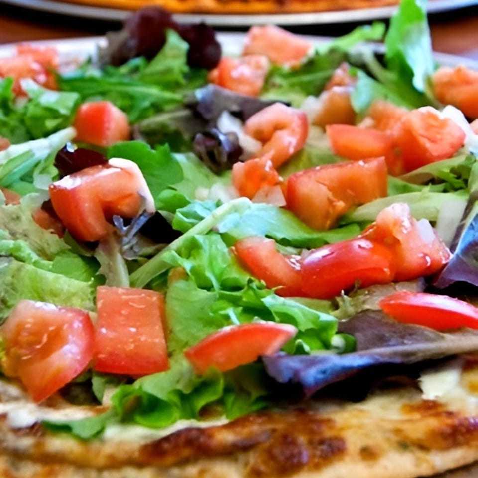 Close-up of a Bada Bing Pizzeria pizza topped with fresh green lettuce and diced red tomatoes.